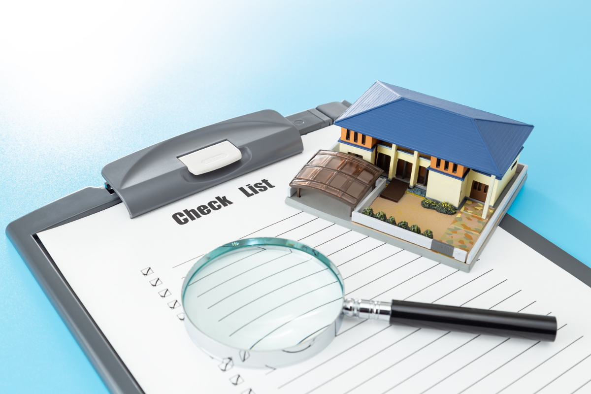 Dividing real estate checklist with model home and magnifying glass, representing property evaluation and asset division planning